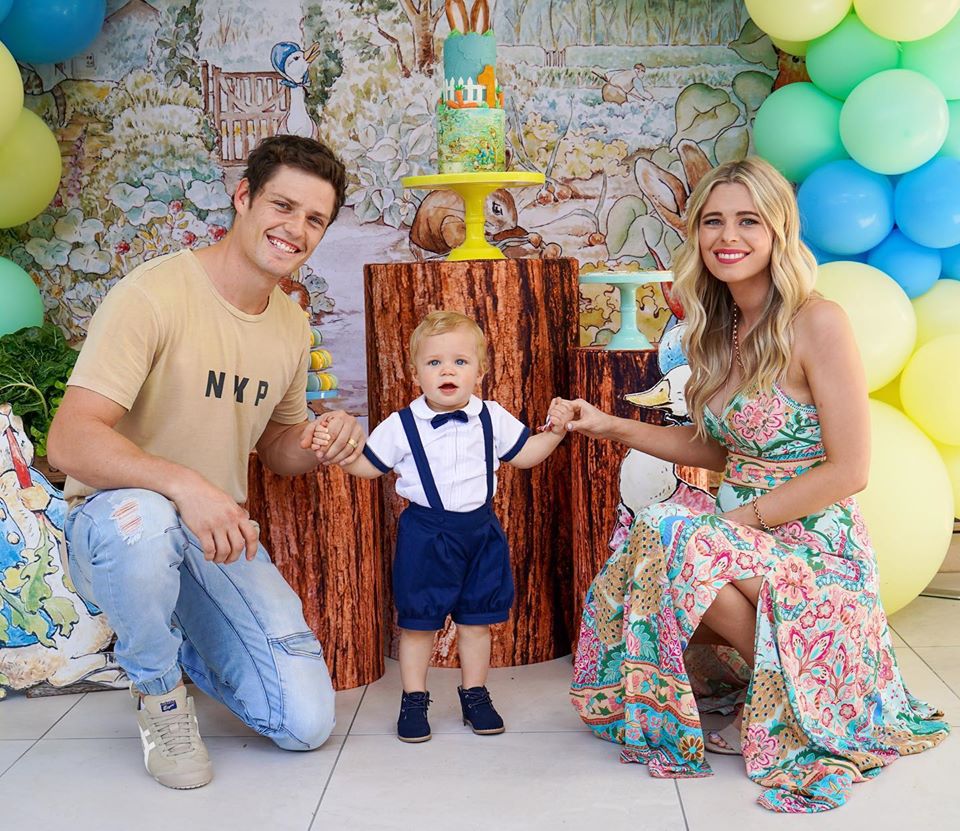 Parents with toddler posed in front of photo wall