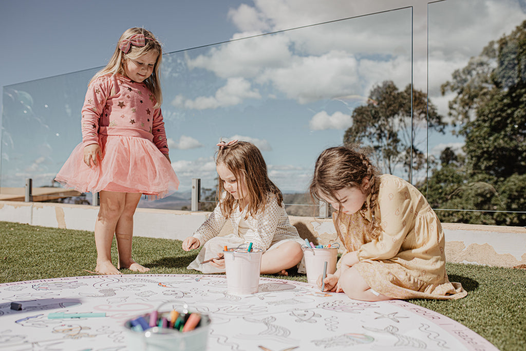 Three girls colouring in a large ground colouring page