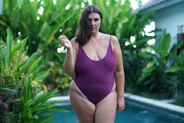 curve model wearing byron one piece swimsuit in bordeaux posing in pool villa 