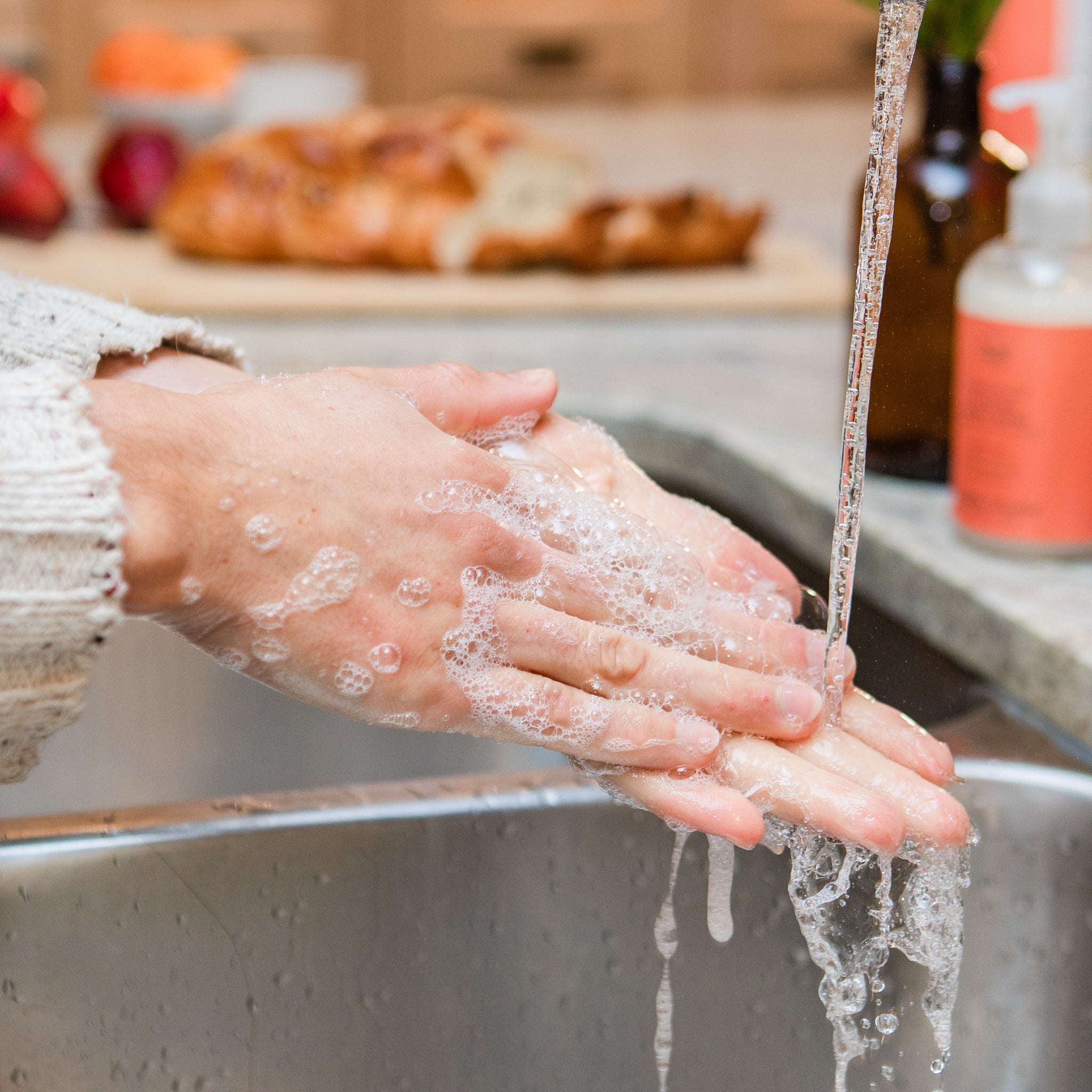 Sudsy hands being washed in the kitchen with Rocky Mountain Soap Company's all natural lactic acid Antibacterial Kitchen Hand Wash liquid soap. 