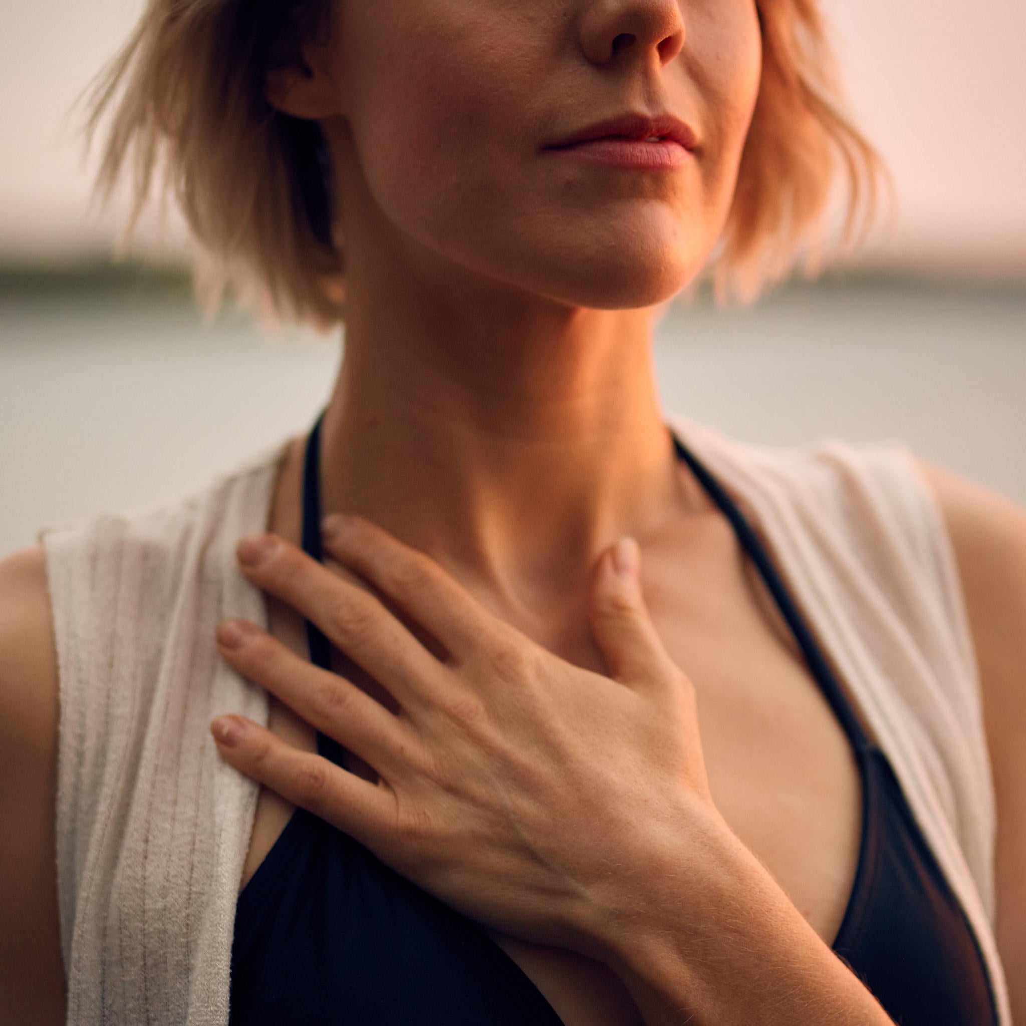 Woman standing holding her hand to her chest. 