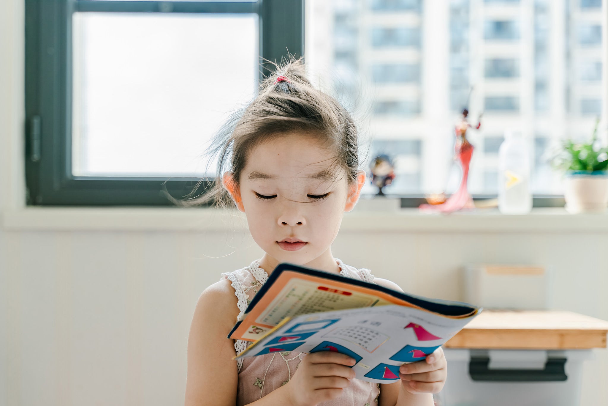 Image of little girl of asian descent reading a book. 
