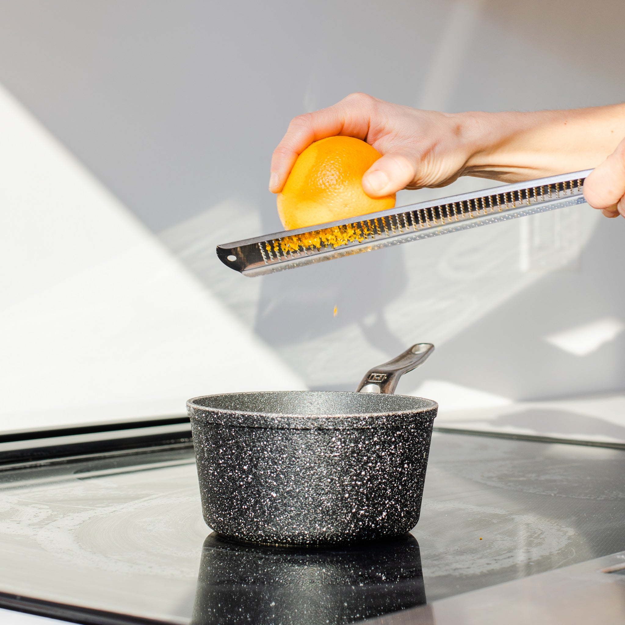 A hand grates orange zest into a pot, an ingredient in this holiday cookie recipe inspired by Rocky Mountain Soap Company's Orange Cardamom scent. 