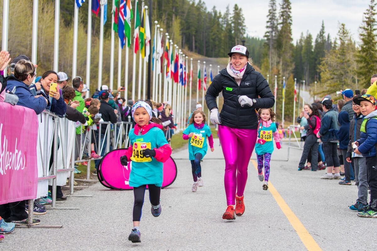 A grown woman running a race next to a small girl. 
