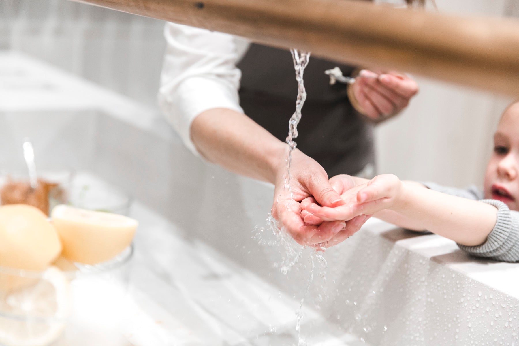 Image of child's hands being rinsed at sink. 