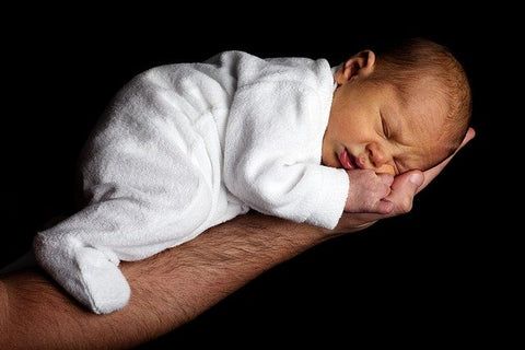 An arm of a man holding a sleeping baby