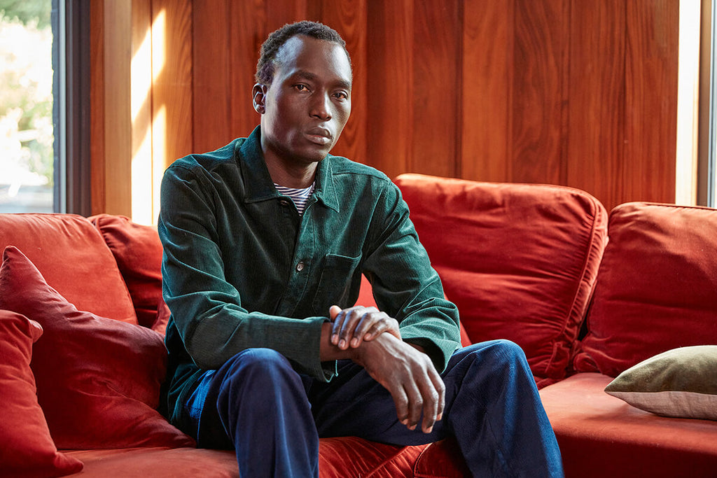 Denis Okwera modelling a rich green navy corduroy Hockney jacket for Oliver Spencer.