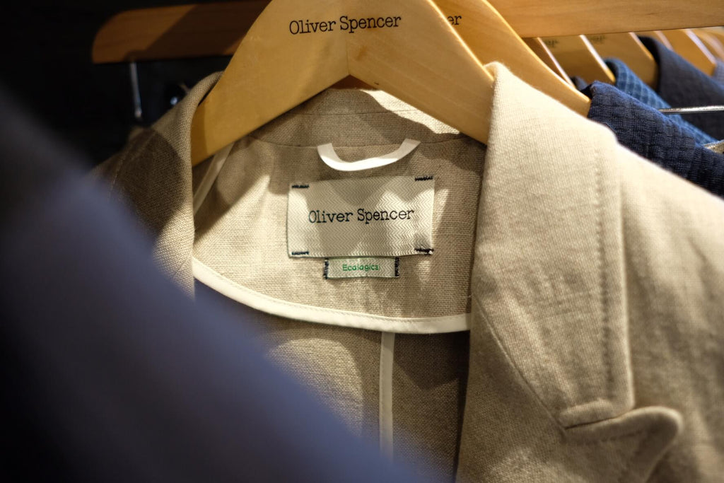 A close-up image of an Oliver Spencer linen jacket displaying an organic cotton tag.