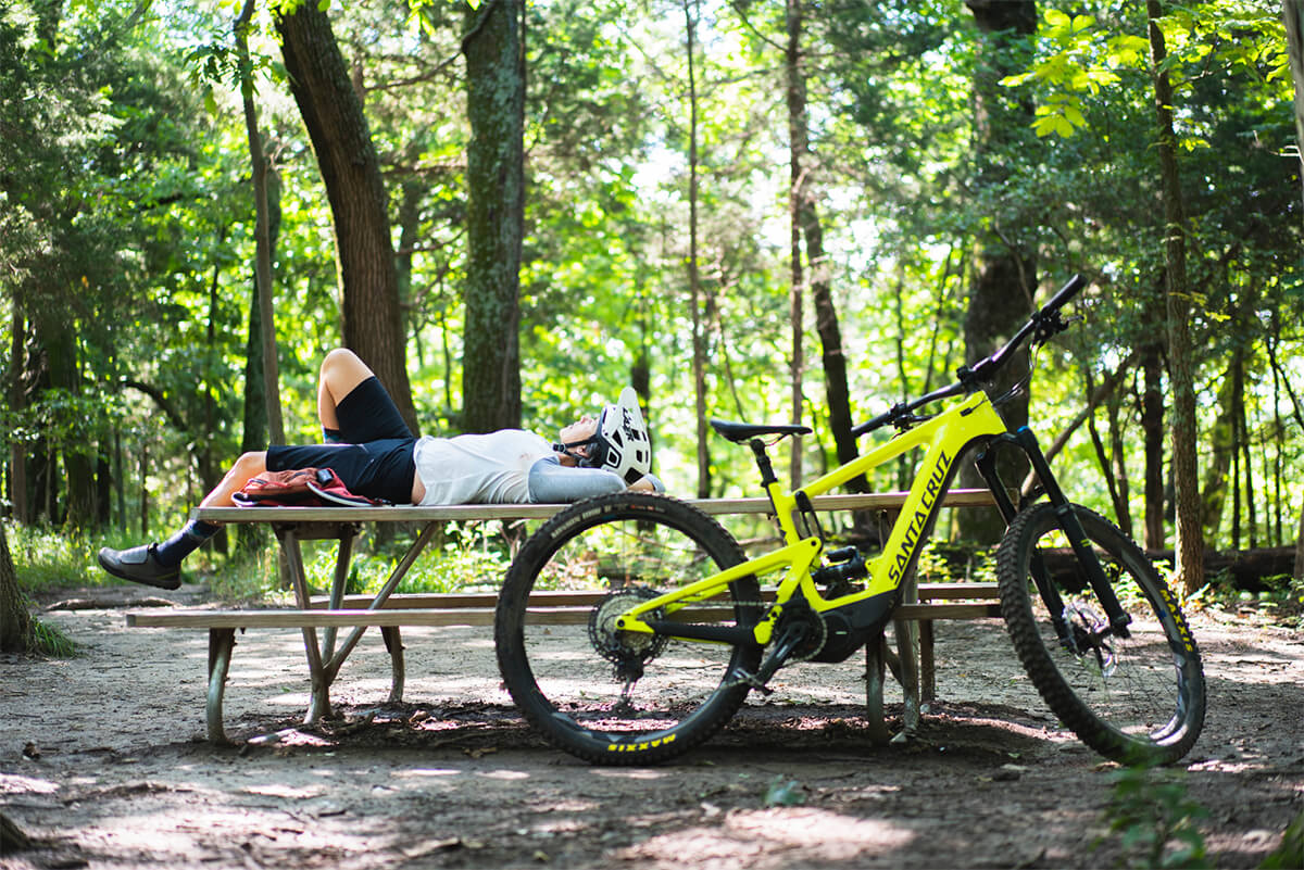 Relaxing on a park bench mid mountain bike ride with a Santa Cruz e mountain bike