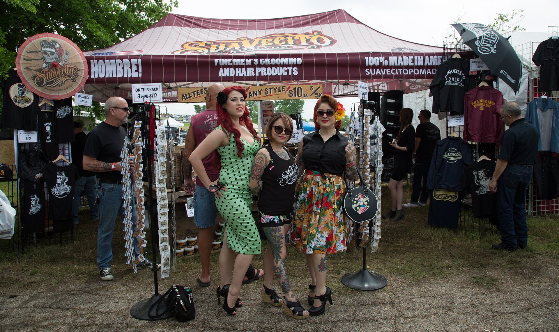 Three great looking girls posing in front of the Suavecito Pomade booth