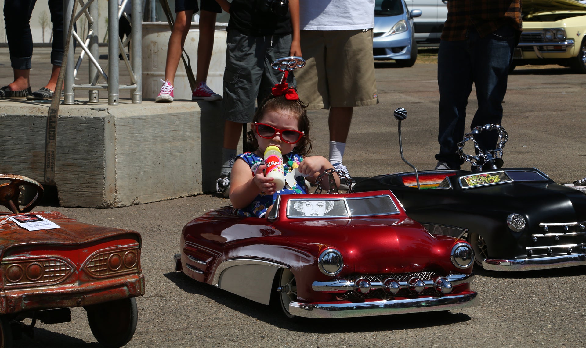 A lil lady enjoying the carshow in her toy car