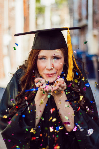 Graduate women blowing confetti
