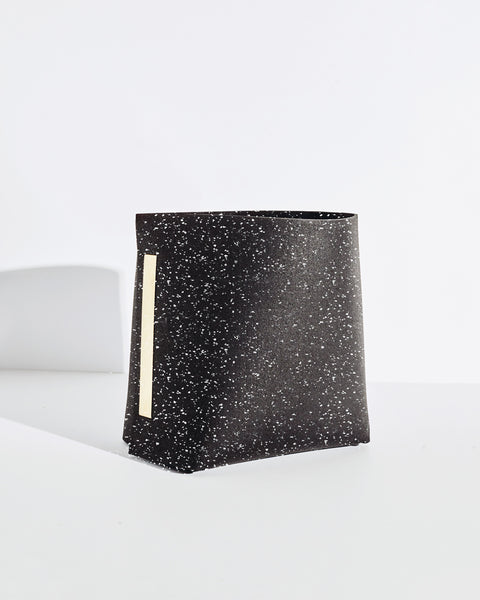 Speckled black rubber and brass bin on white background. 