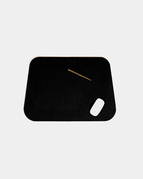 Rounded corner black rubber desk mat with brass pen and white mouse on white background.