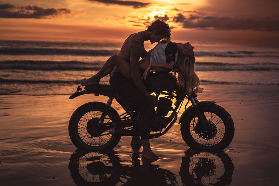 man kissing woman on motorcycle on beach, vacation sex story