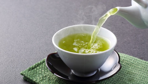 liquid green tea being poured in a teacup