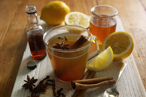 A cup of hot toddy surrounded with ingredients