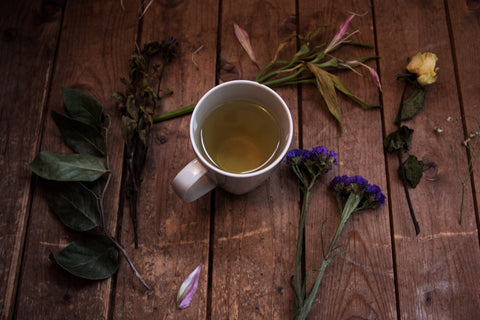 cup of tea surrounded by flowers and twigs