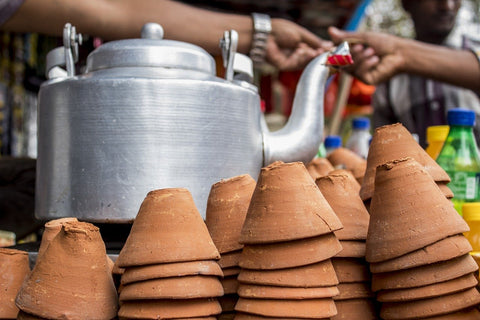 a kettle and small clay cups for chai tea