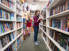 Girls reading in aisle of books