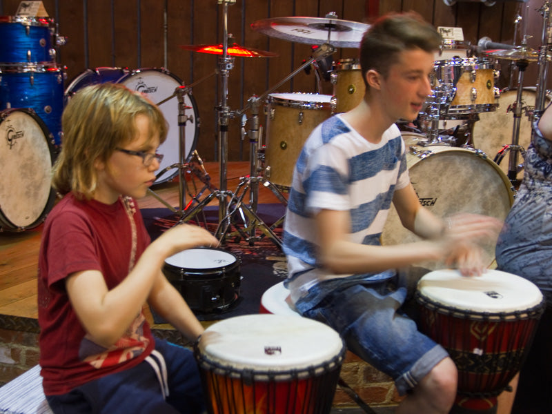 Drummers play djembes at drum shop UK