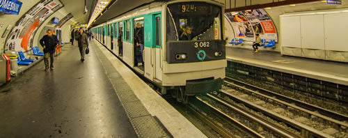 Two people walk along the subway platform in Paris as the metro departs the station.