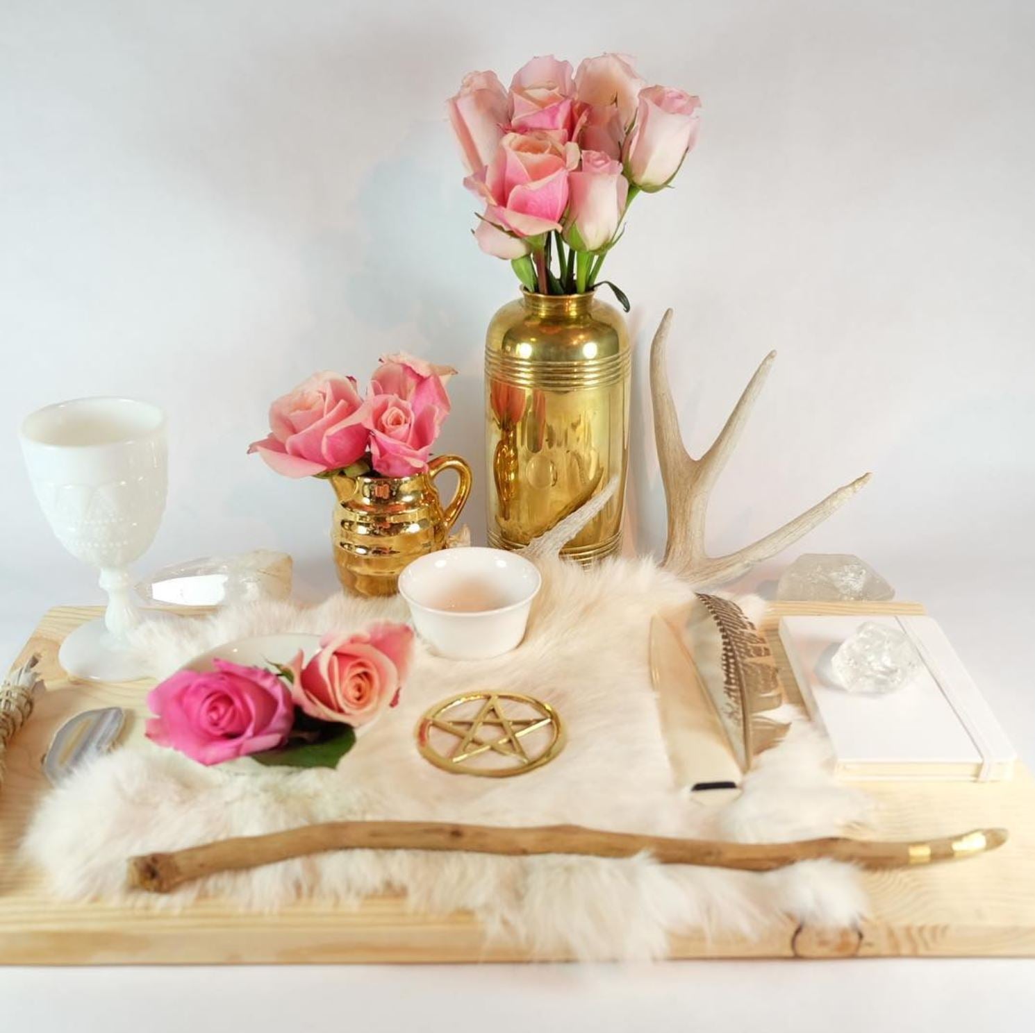 a witch altar with pink roses and a gold pentacle and clear quartz