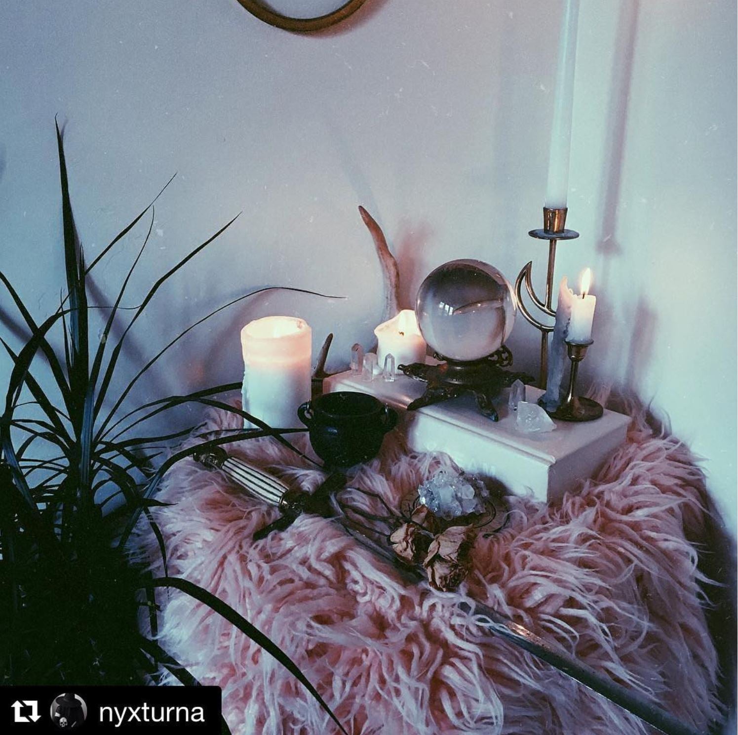 a witch altar with a fuzzy pink chair and candles