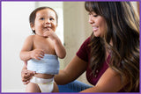 Smiling baby wearing a Happi Tummi in the arms of his mother.