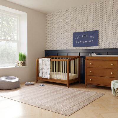 Babyletto's Sprout 4-in-1 Convertible Crib next to a dresser in -- Color_Chestnut / Natural