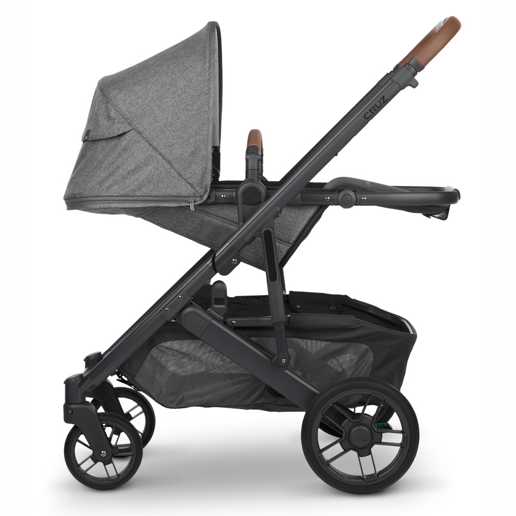 Side view of fully reclined, parent-facing uppababy cruz v2 stroller with black frame and heather grey fabric -- Color_Greyson