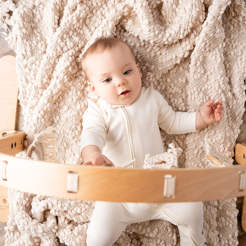 Top view of baby underneath the Finn + Emma Play Gym in -- Color_Natural / Macrame