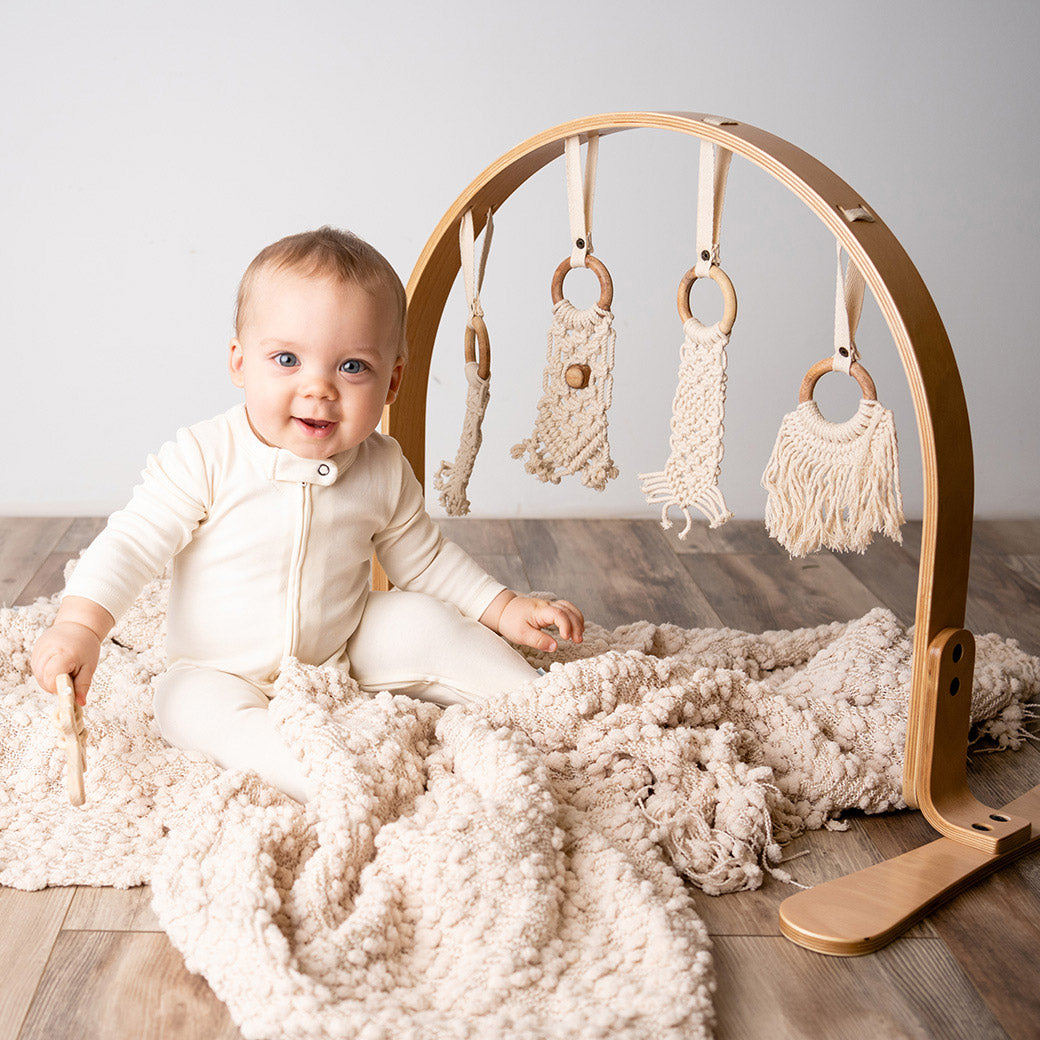 A baby sitting next to the Finn + Emma Play Gym in -- Color_Natural / Macrame