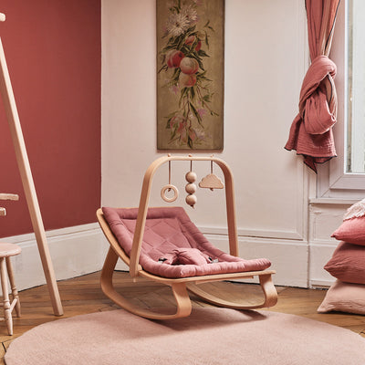 Charlie Crane LEVO Baby Rocker in Bois de Rose / Beech in a display in a baby room, with attachments above head for baby to play with -- Color_Bois de Rose _ Beech