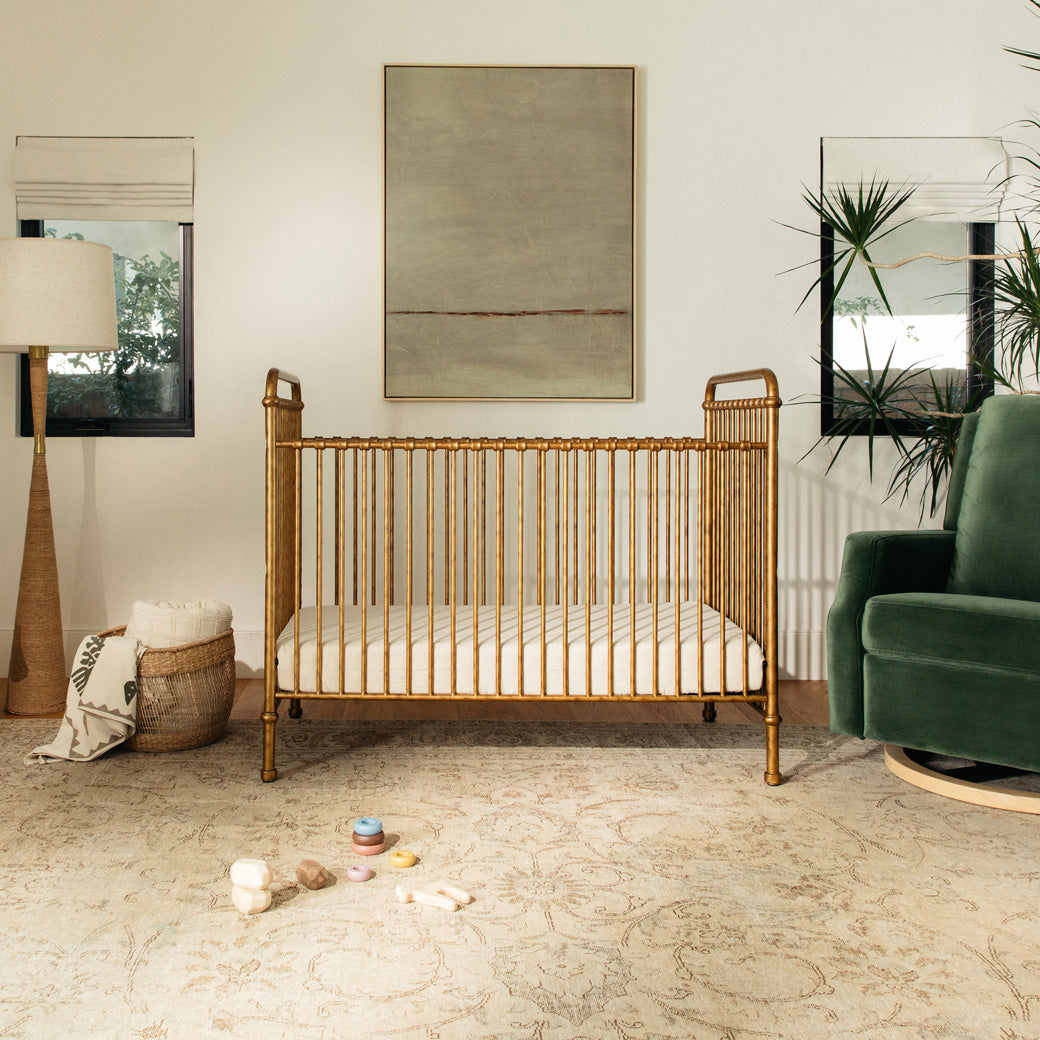 Namesake`s Abigail 3 in 1 Crib next to lamp and recliner  in -- Color_Vintage Gold