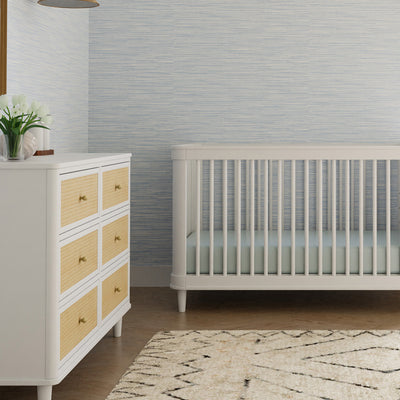 Namesake's Marin 6 Drawer Dresser next to a crib  in -- Color_Warm White/Honey Cane