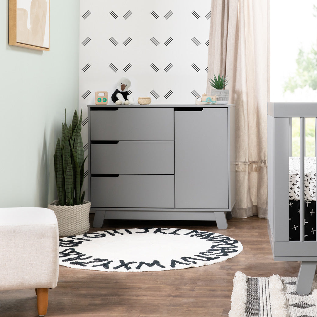 Lifestyle front view of The Babyletto Hudson Changer Dresser next to a plant and window in -- Color_Grey