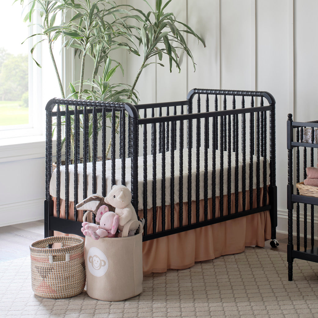 Lifestyle side view of the DaVinci’s Jenny Lind Crib next to a window and plant in -- Color_Ebony