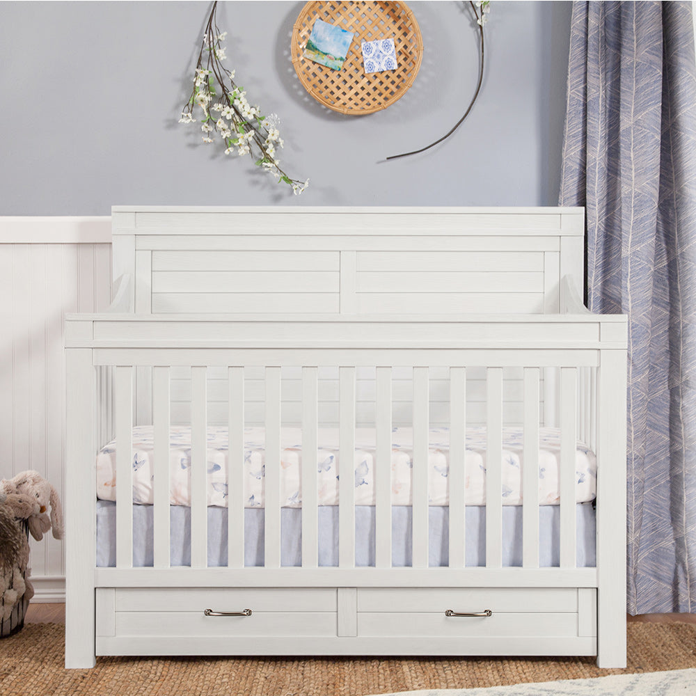 Front view of Namesake's Wesley Farmhouse 4-in-1 Convertible Storage Crib in a kid's room in -- Color_Heirloom White