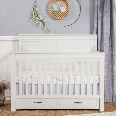 Front view of Namesake's Wesley Farmhouse 4-in-1 Convertible Storage Crib in a kid's room in -- Color_Heirloom White