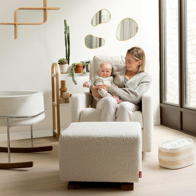 mother holding child in como glider next to a bassinet -- Lifestyle