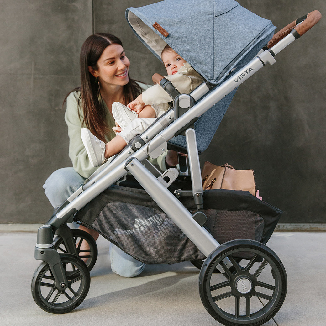 woman kneeling beside the vista v2 stroller in Gregory while looking at child in stroller -- Color_Gregory