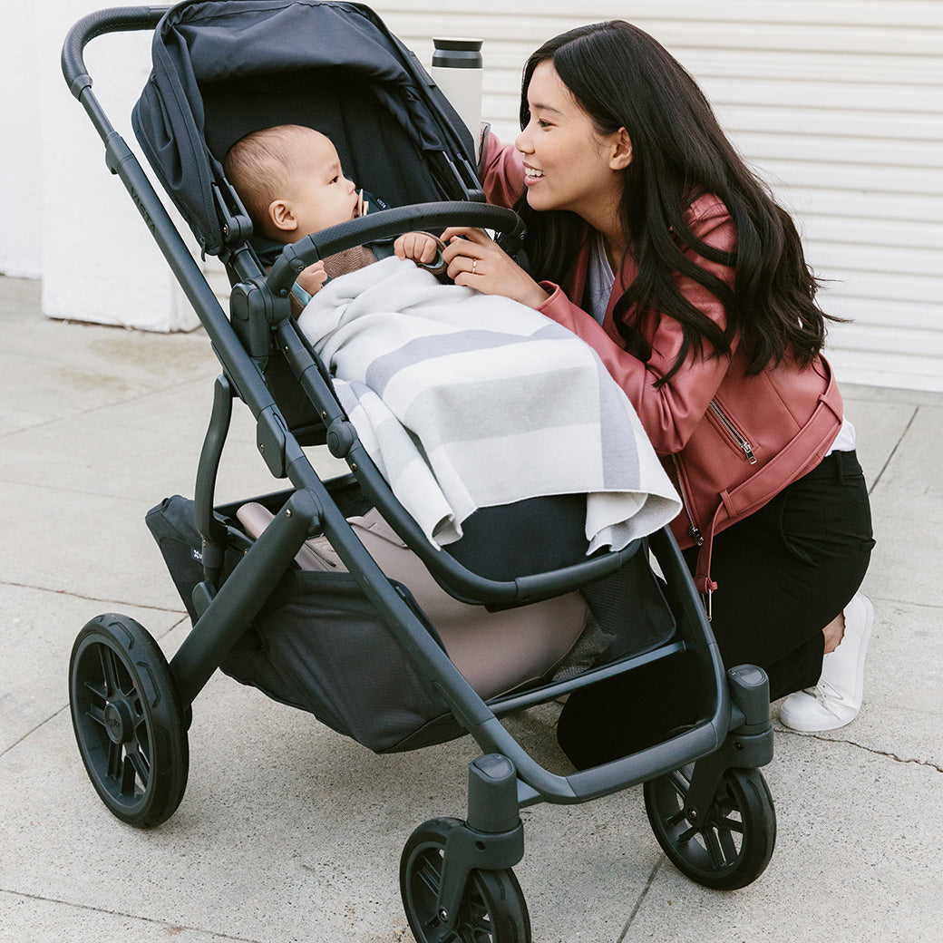 woman kneeling beside the vista v2 stroller in Jake while looking at child in stroller -- Color_Jake