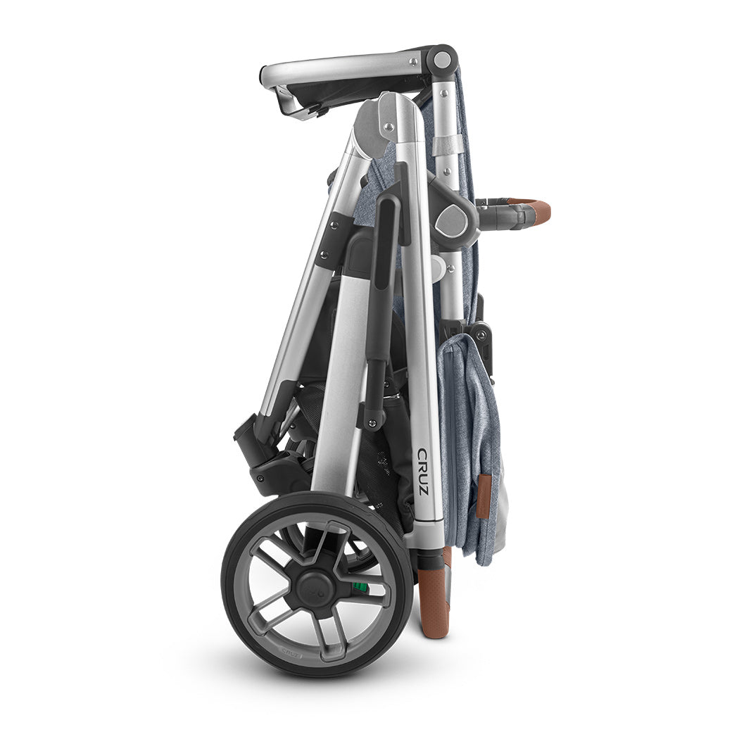 Side view of the UPPAbaby CRUZ V2 stroller in bluish gray and black, folded and standing on its own  -- Color_Gregory