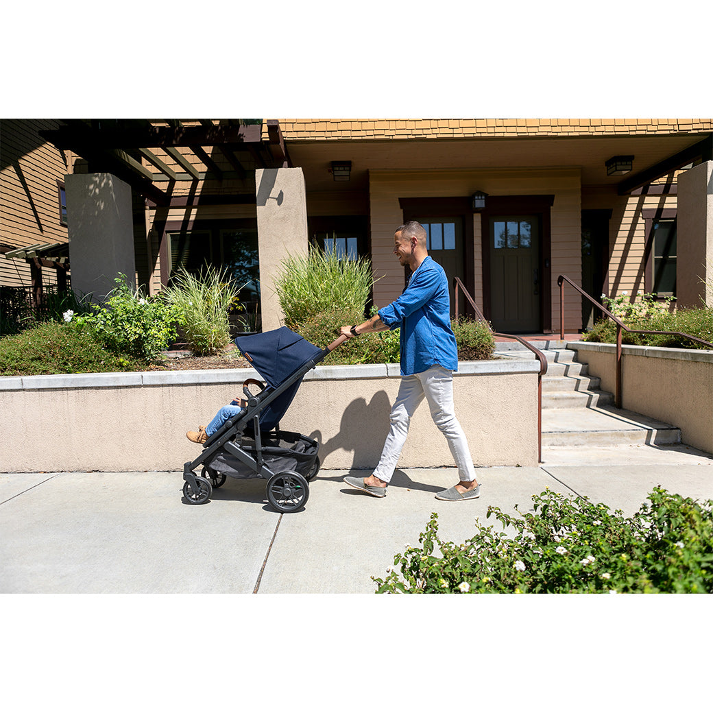 Father with short hairwearing khakis and a long sleeve blue shirt, pushing a toddler in a forward facing uppababy cruz v2 stroller -- Lifestyle