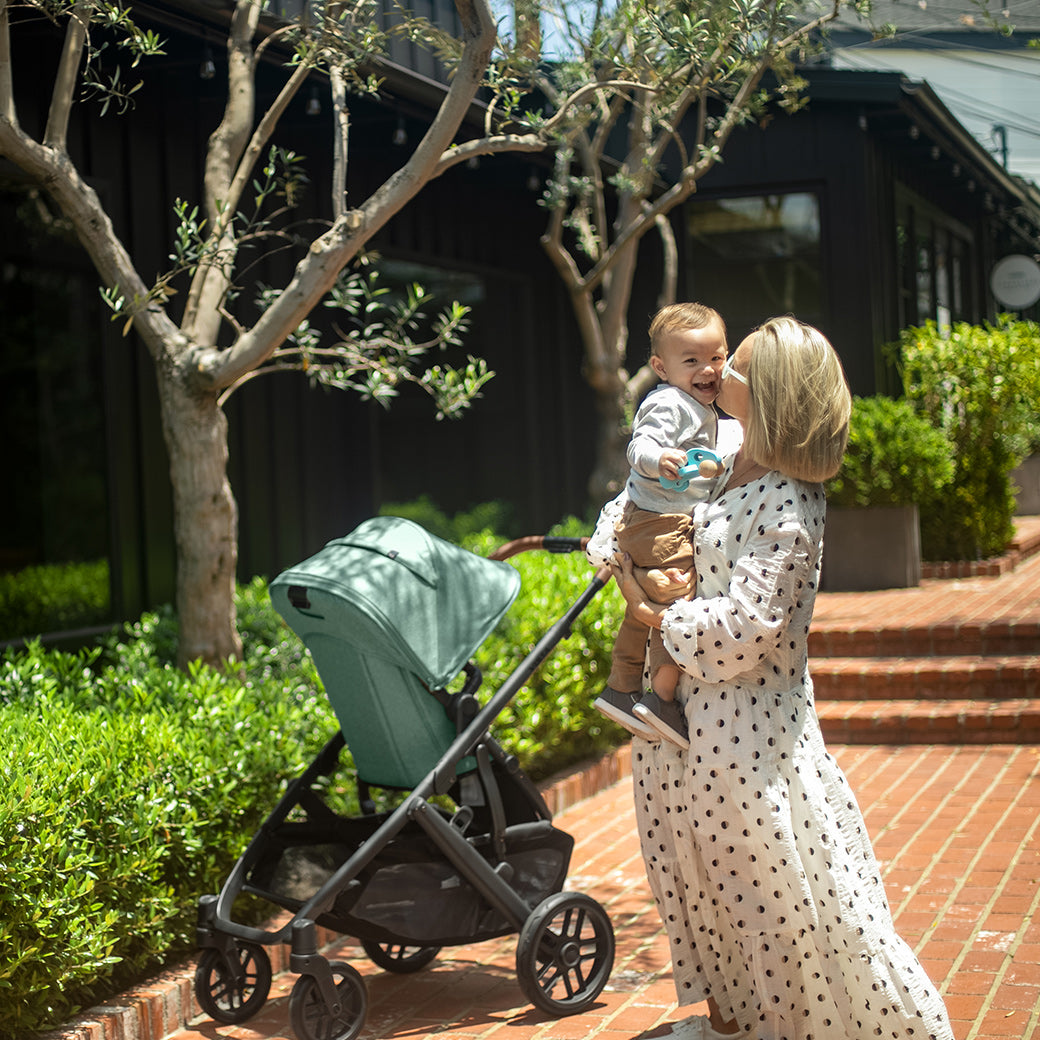 Woman holding the child and the vista v2 stroller beside -- Color_Gwen