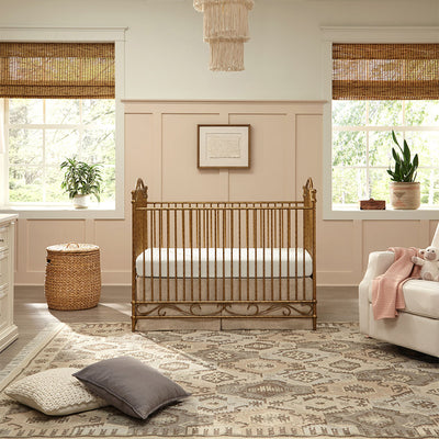 Namesake's Camellia 3-in-1 Convertible Crib in a room next to a recliner and basket in -- Color_Vintage Gold