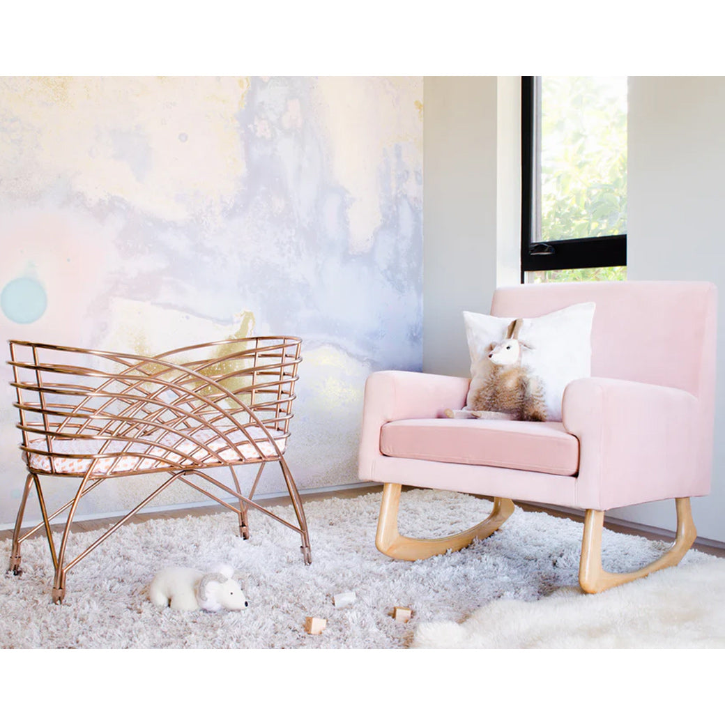 Nursery Works Sleepytime Rocker next to a bassinet in -- Color_Blush Velvet with Light Legs