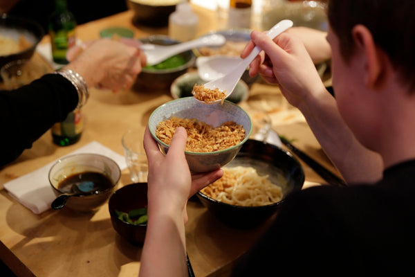 Diner adding ingredients to the soba noodles
