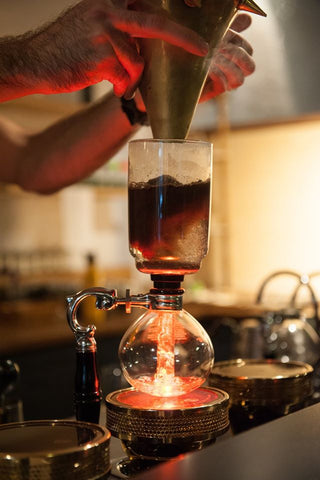 Adding ground coffee to siphon